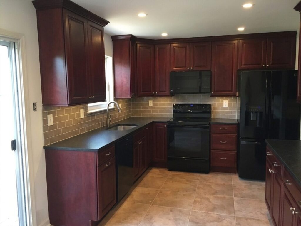 image showing kitchen with cherry wood cabinets, black countertops, taube tile backsplash and tile floor